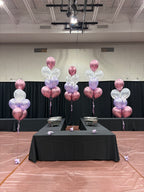 Cinq bouquets de ballons aux couleurs rose, mauve et blanc sur une table de banquet pour un évènement de graduation à Québec