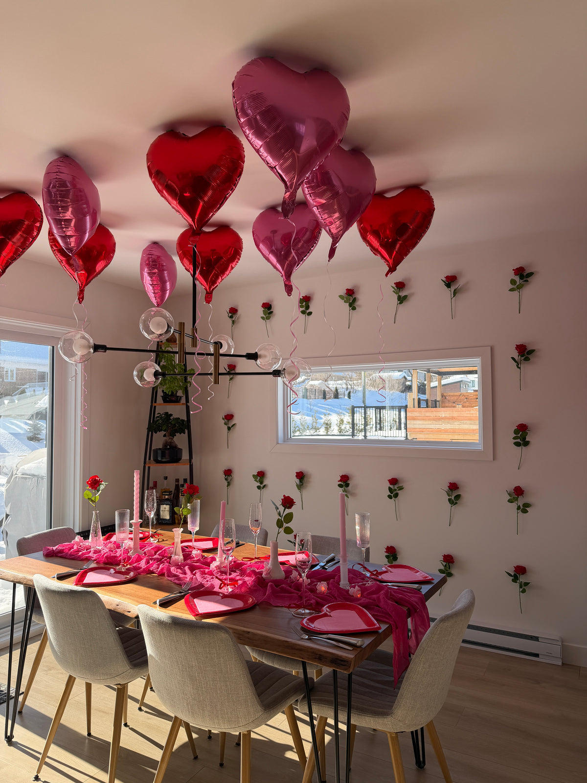 Table de cuisine décorée pour la Saint -Valentin avec des ballons au plafond en forme de coeur rouges et rose